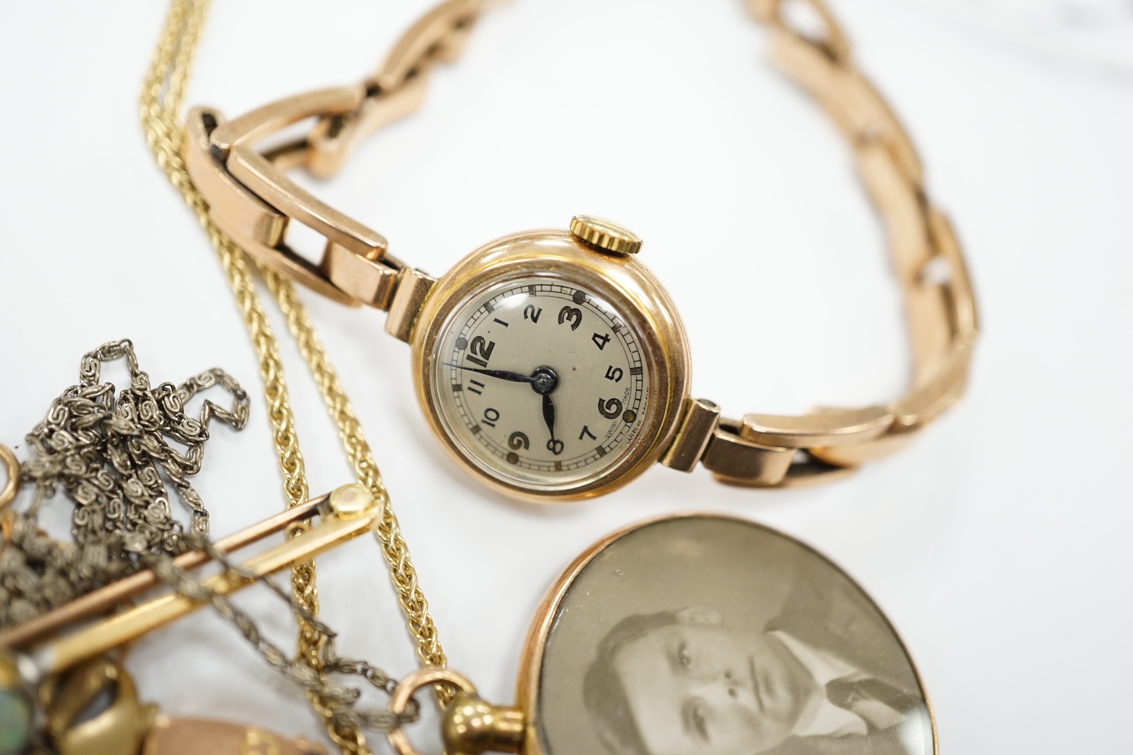 A lady's yellow metal manual wind wrist watch, on a 9ct expanding bracelet, a modern 9ct gold and white opal set pendant, on a 375 chain and other minor jewellery including a pair of 9ct gold knot earrings.